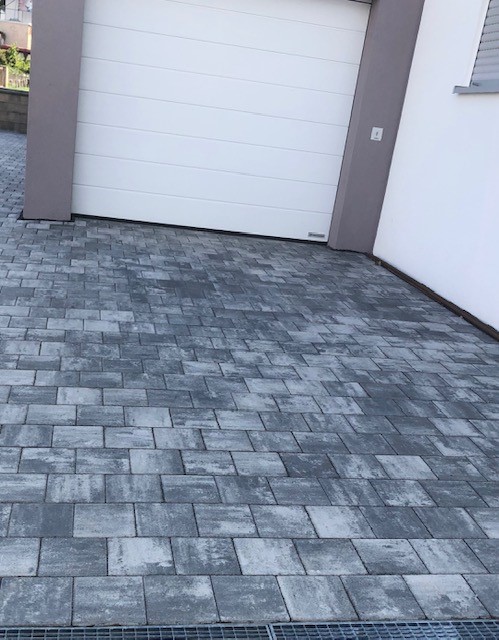 Neu verlegtes graues Betonpflaster als Stellfläche vor einer Garage